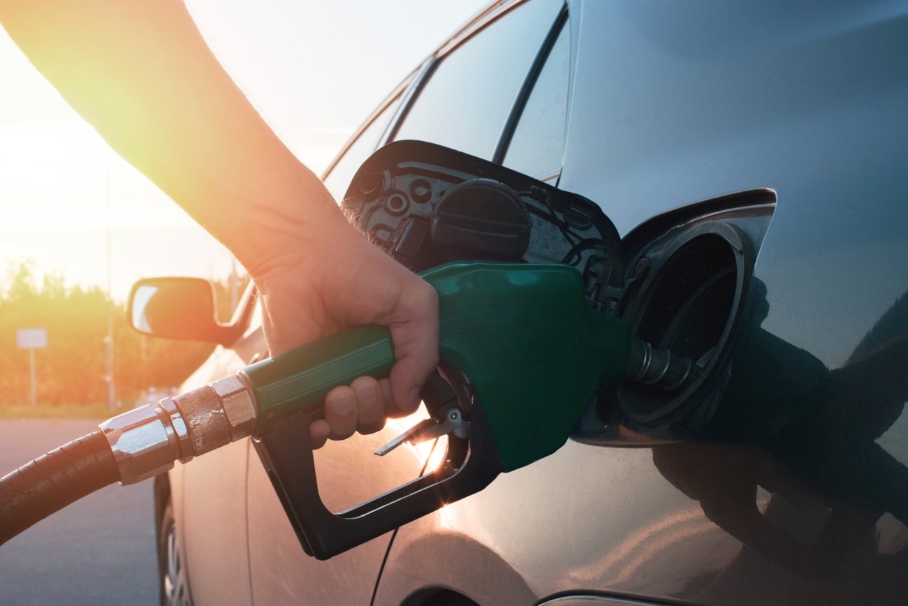 Hånd som holder drivstoffpumpe og fyller drivstoff på biltank